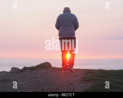 Uomo anziano incorniciata dal tramonto vista posteriore Foto Stock