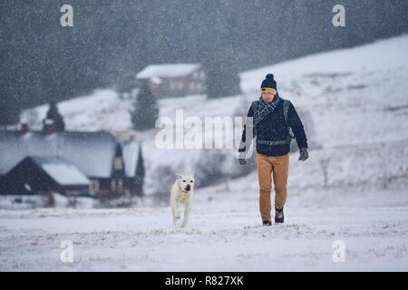 L'amicizia tra pet proprietario e il suo cane. Giovane uomo a camminare con il labrador retriever nel paesaggio invernale. Montagne di Jizera, Repubblica Ceca Foto Stock