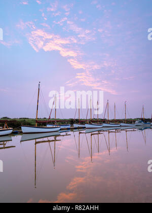 Una linea di identici e barche a vela all'alba in una tranquilla mattina di primavera. Foto Stock