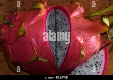 Drago a fette di frutta, pitaya blanca o bianco-arricchito e rosa-pelato mature pitahaya frutto anche chiamato Hylocereus undatus sul tavolo di legno Foto Stock