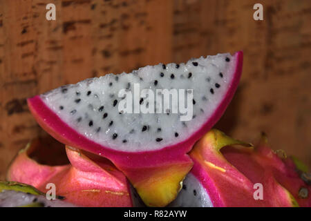 Macro shot di fetta di dragon frutto nella parte anteriore del sughero sfondo , pitaya blanca o bianco-arricchito e rosa-pelato mature pitahaya frutto anche chiamato hylo Foto Stock