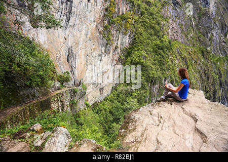 Giovane donna godendo la vista del Ponte di Inca e cliff percorso nei pressi di Machu Picchu in Perù. Il ponte è una parte di un sentiero di montagna che capi ad ovest di M Foto Stock