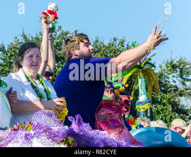 I festaioli buttare perle per la folla come loro il galleggiante si sposta lungo Canal Street in Mobile, Alabama, durante il Joe Caino parata del giorno a Mardi Gras. Foto Stock