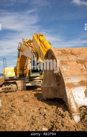 Escavatore per movimento terra preparando il cantiere per la costruzione del suolo. Convogliatore dettaglio Foto Stock