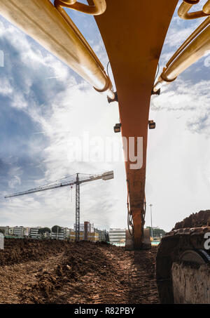 Vista da sotto il movimento terra braccio escavatore in cantiere. Macchinari per la costruzione di sfondo Foto Stock