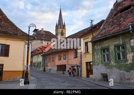 Tipiche pietre ciottoli street della città di Sibiu Romania, con case colorate, campanile e la luce post Foto Stock