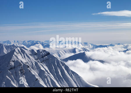 Montagne innevate in nuvole e il bel cielo azzurro a Nizza il giorno d'inverno. Montagne del Caucaso, Georgia, regione Gudauri. Foto Stock