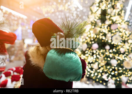 Santa da dietro con borsa regalo su sfondo bokeh di albero di natale. Foto Stock