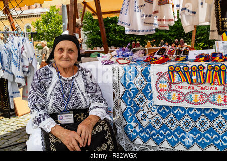 Cluj Napoca, Romania - 27 Luglio 2018: una donna vestita di tradizionali abiti rumeno, vendita tradizionale rumena di vestiti e souvenir in un bazar Foto Stock