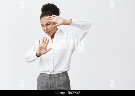 Wow, ruotare la luce spenta l'uomo. Disturbato e orinato AFRICAN-AMERICAN imprenditrice in camicia bianca e pantaloni, sollevando le mani per coprire la faccia da scintille di ligtning, accigliata da healight sulla vettura Foto Stock