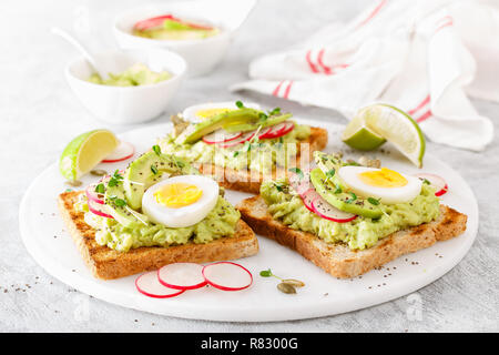 Toast con avocado guacamole, rafano fresco, uova sode, chia e semi di zucca. La dieta la prima colazione. Delizioso e sano a base di piante alimentari. Primo piano. Bann Foto Stock