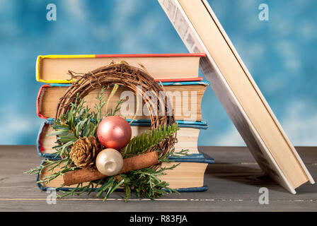 Gruppo di libri su una superficie di legno con una ghirlanda di Natale ripiegato verticalmente su uno sfondo verde Foto Stock