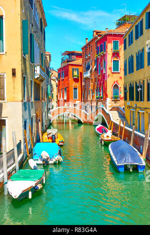 Pittoresco canale con un piccolo ponte e barche ormeggiate a Venezia, Italia Foto Stock