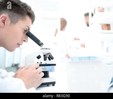 Ricerca maschio scienziato guarda a campioni biologici sotto micros Foto Stock