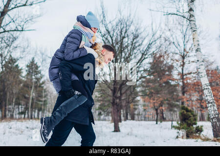 Guy dando la sua fidanzata sovrapponibile in inverno foresta. Giovani amare giovane avendo divertimento all'aperto. Le persone felici rilassante Foto Stock