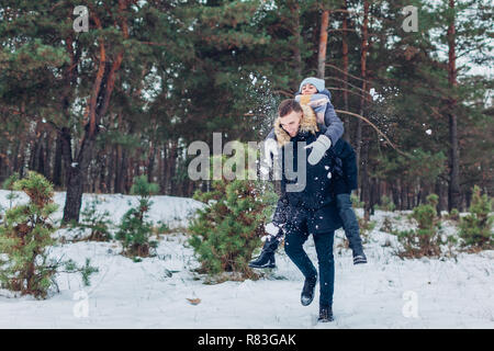 Guy dando la sua fidanzata sovrapponibile in inverno foresta. Giovani amare giovane avendo divertimento all'aperto. Le persone felici rilassante Foto Stock