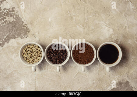 Quattro tipi di caffè non torrefatto, fagiolo, terra e uno in coppa Foto Stock