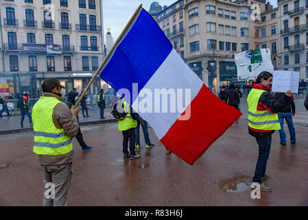 Giubbotti di giallo (Gilets Jaunes), protesta contro le tasse sul carburante, il governo e il presidente francese Macron. Un manifestante è stato sventola bandiera francese a Lyon, Francia Foto Stock