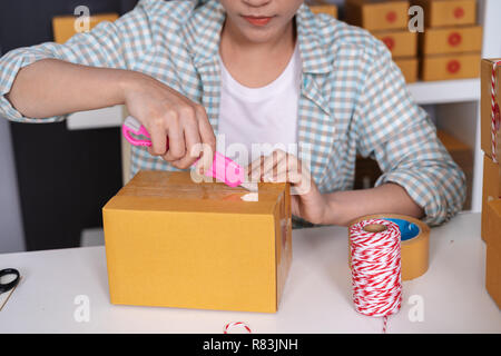 Giovane donna con coltello aprire il pacco di consegna Foto Stock