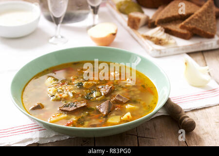 Rassolnik, tradizionale zuppa di Russo, servito con vari snack e la vodka. Stile rustico. Foto Stock