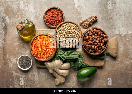 Vista dall'alto di legumi, zenzero, chia semi e avocado su tavola di legno con sfondo rustico Foto Stock