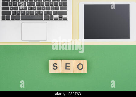 Vista superiore della tavoletta digitale e laptop vicino a cubetti di legno con scritte di seo Foto Stock