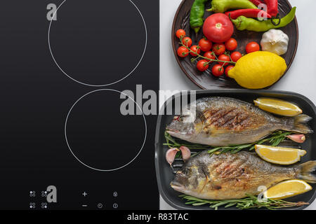 Vista superiore del pesce fritto delizioso con rosmarino, limone e verdure fresche Foto Stock