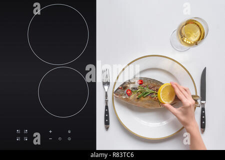 Ritagliato colpo di persona in possesso di limone e mangiare pesce fritto delizioso Foto Stock