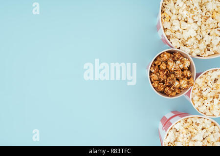 Vista superiore di cestelli con popcorn in fila verticale isolato su blu Foto Stock