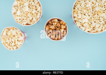 Vista dall'alto di strisce di benne con popcorn fresco isolato su blu Foto Stock