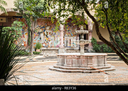 Cortile interno con fontana presso l'Instituto Allende in San Miguel De Allende, Messico. Il murale in background è dal leggendario Muralista Messicano David Alfaro Siqueiros. Foto Stock