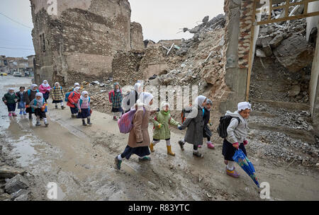 Ragazze fanno il loro modo a scuola in mezzo alle macerie della vecchia città di Mosul, Iraq, che era stato devastato durante la guerra contro ISIS. Foto Stock