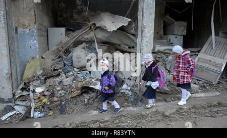 Ragazze fanno il loro modo a scuola in mezzo alle macerie della vecchia città di Mosul, Iraq, che era stato devastato durante la guerra contro ISIS. Foto Stock