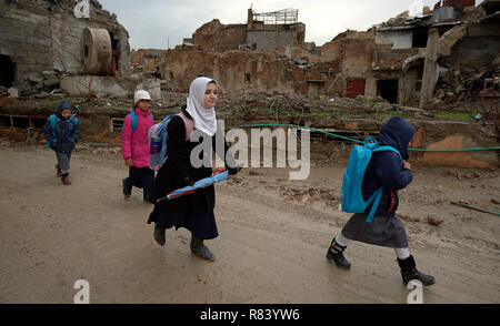 Ragazze fanno il loro modo a scuola in mezzo alle macerie della vecchia città di Mosul, Iraq, che era stato devastato durante il 2017 Battaglia di Mosul. Foto Stock