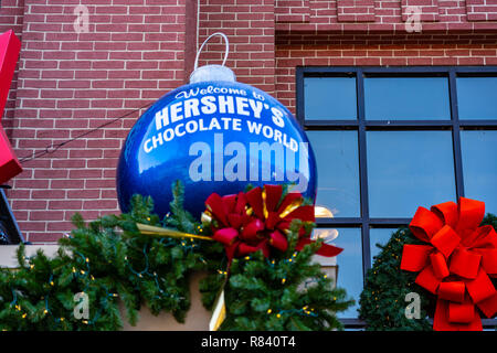 Hershey, PA, Stati Uniti d'America - 11 dicembre 2018: una grande palla di Natale è sul display esterno in corrispondenza dell'ingresso al mondo del cioccolato. Foto Stock