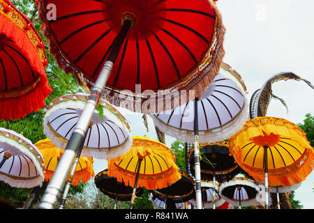 Gruppo di belle bandiere Balinese e ombrelloni alla cerimonia di celebrazione nel tempio indù. Design tradizionale festival delle arti e cultura dell'isola di Bali Foto Stock