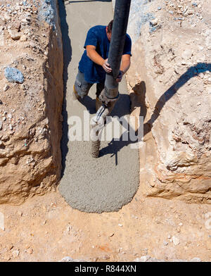 Costruzione edilizia lavoratore colata di cemento o calcestruzzo con il tubo della pompa Foto Stock