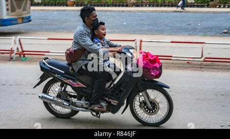 POIPET, Cambogia - Novembre 24, 2017: due piloti: pianto Asian little boy, il capretto con uomo adulto sullo scooter moto. Il varco di frontiera tra la Foto Stock