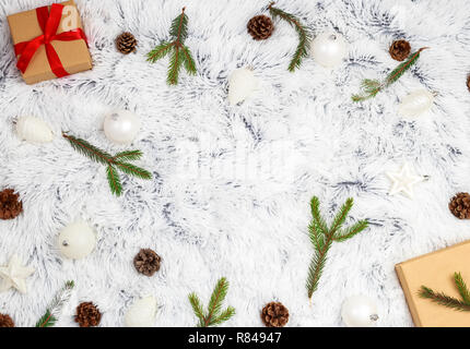 Composizione di natale. Regalo di natale, coperta di maglia, pigne, rami d abete su soffici sfondo bianco. Felice Anno Nuovo, Natale sfondo. Foto Stock