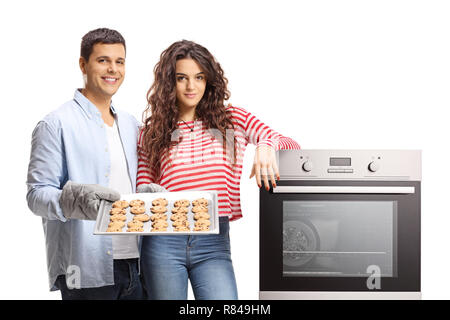 Coppia giovane con un forno e un vassoio di biscotti appena sfornati isolati su sfondo bianco Foto Stock