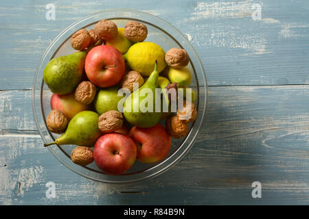 Pila di mele, pere, noci e banane sul blu chiaro Tavolo in legno - primo piano Foto Stock