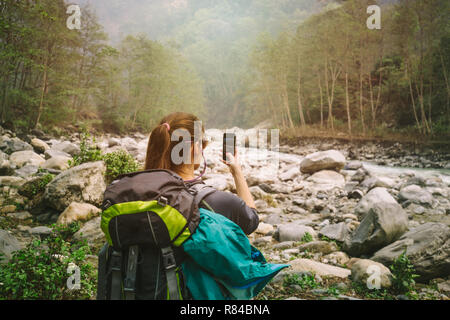 Vista posteriore di un escursionista femmina tenendo fotografia con smart phone Foto Stock