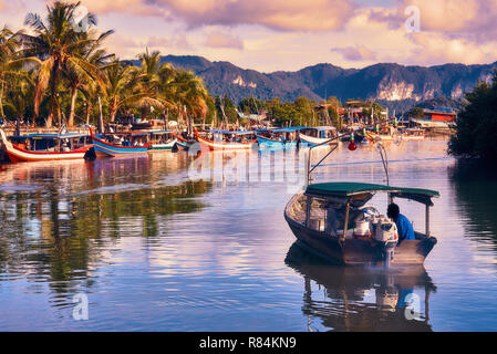 Un pescatore locale si spegne su di una barca dal parco barche in mare per la pesca. Tradizionale asiatica colorate barche da pesca nel villaggio di pescatori. Il Langkawi. Foto Stock