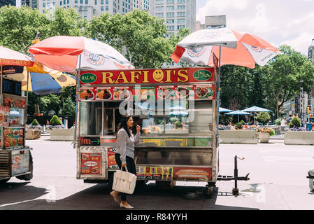La città di New York, Stati Uniti d'America - 25 Giugno 2018: Donna è l'acquisto di cibo al carrello di cibo nelle strade di Manhattan. Foto Stock