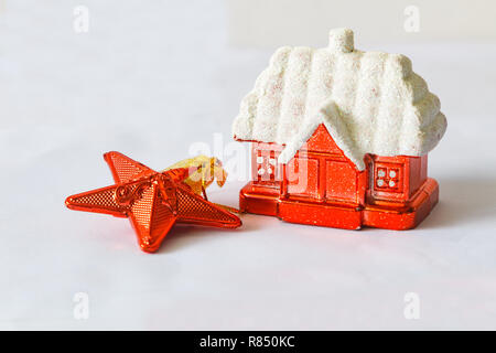 Anno nuovo decorazione rossa rifugio con una coperta di neve tetto e una stella rossa su uno sfondo bianco. Foto Stock