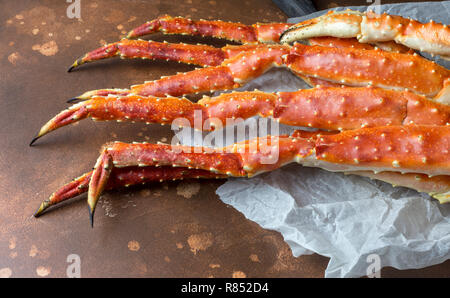 Freschi e saporiti re kamchatka crab's claw sulle imbarcazioni di carta a sfondo marrone Foto Stock