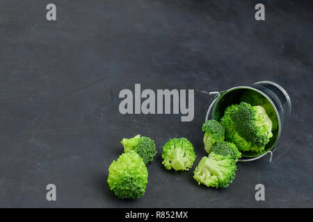 Placer broccoli verdi segmenti da un piccolo cucchiaio. Mangiare sano pattern su sfondo scuro. Spazio Copia vista dall'alto. Cibo vegetariano. Foto Stock