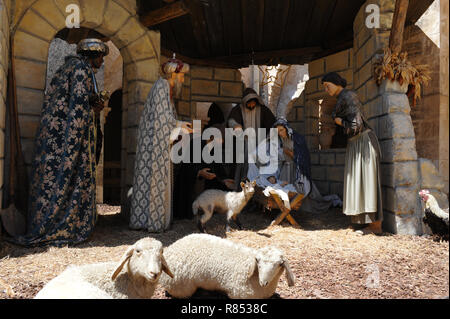 La nascita di Gesù a Betlemme il giorno di Natale con tre wisemen in piena vesti regali del cuscinetto per il Bambino nella mangiatoia vicino a Maria e Giuseppe in pecore stabile. Foto Stock