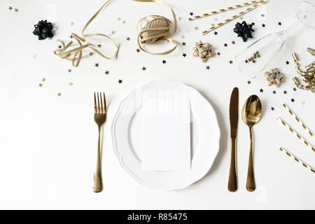 Anno nuovo, stile natale nero e oro messa in tavola con la piastra, posate, coriandoli stelle e champagne bicchiere di vino. Parte della decorazione. Il menu del ristorante la scheda vuota mockup. Appartamento laico, vista dall'alto. Foto Stock