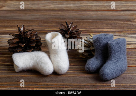 Giocattoli stivali di feltro e pigne marrone su sfondo di legno Foto Stock